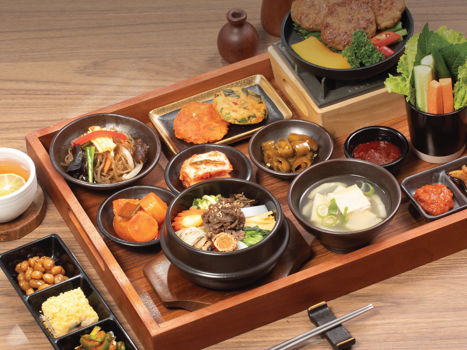 A full Korean table tray with dolsot bibimbap, soup and banchan